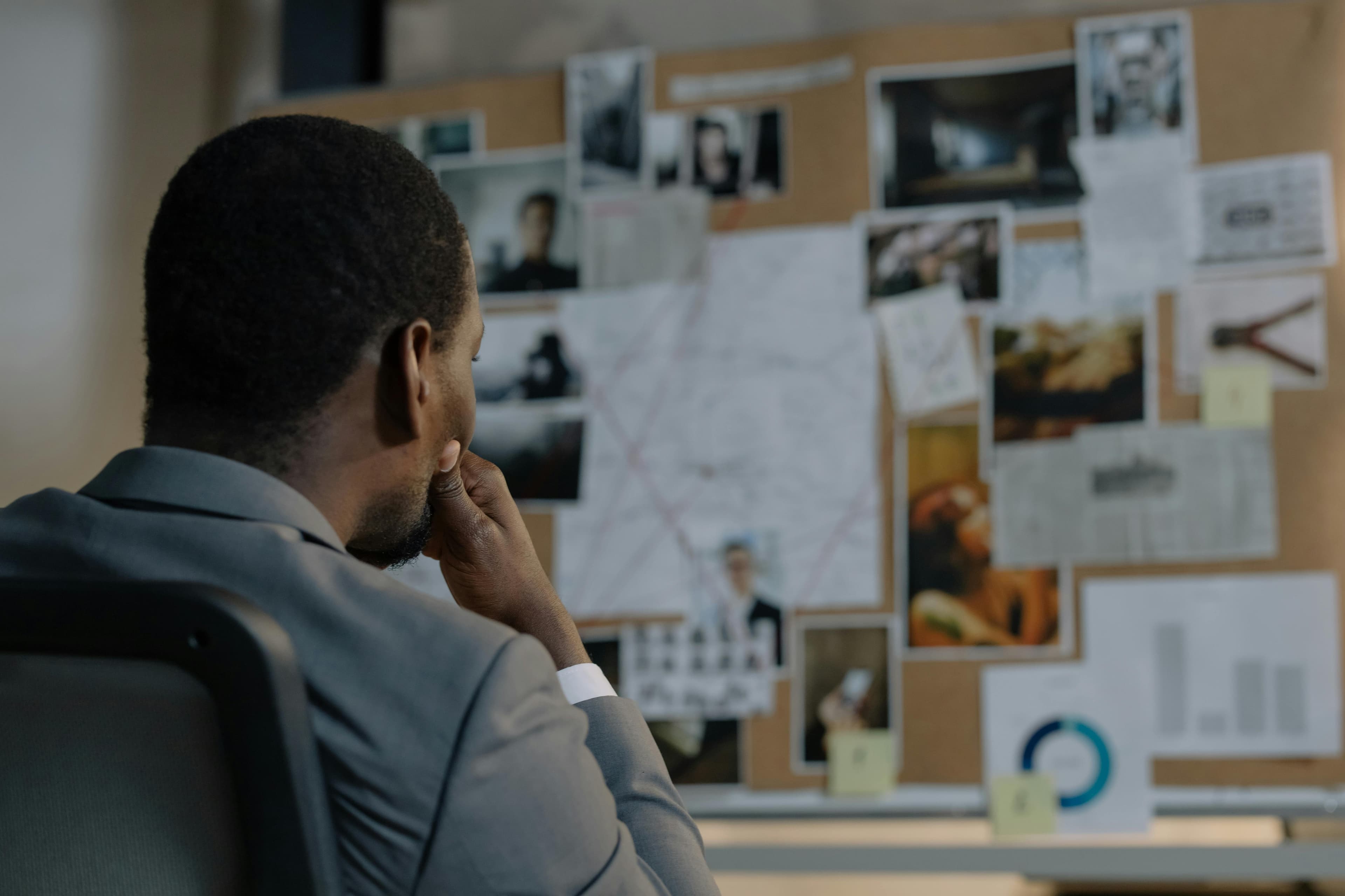 Investigator studying a case board of photographs, notes, and charts